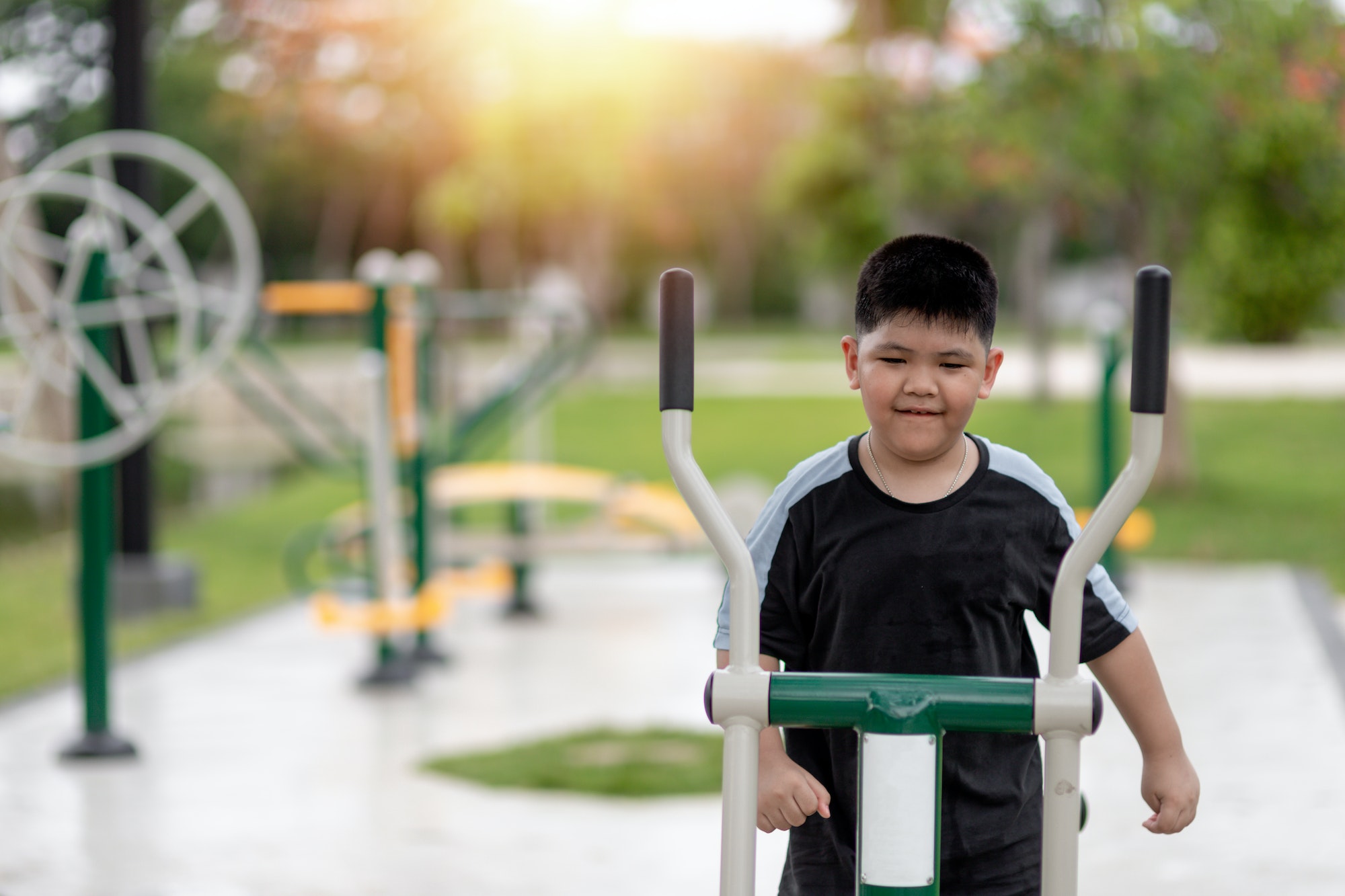 fat boy trains on fitness equipment in the park